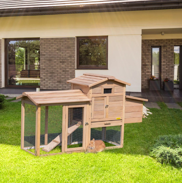 A rabbit is resting beside the rabbit hutch.